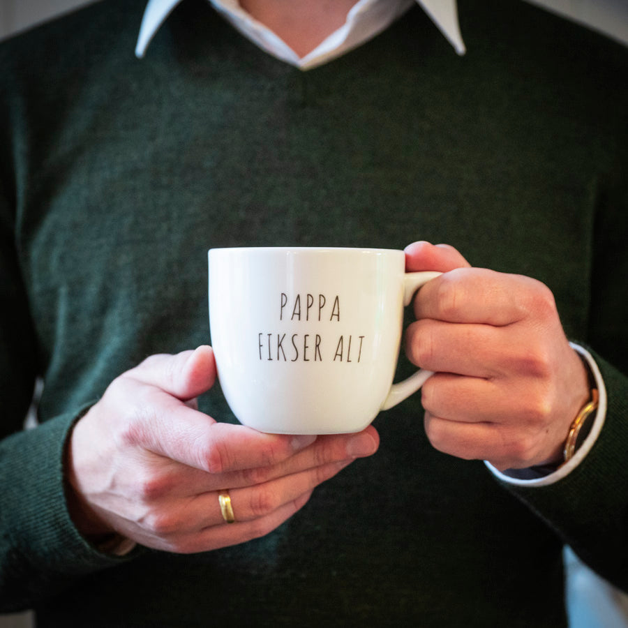 Hvit krus med teksten 'Pappa fikser alt', perfekt som gavetips til farsdag. En praktisk gave som viser omtanke og kjærlighet til pappa.