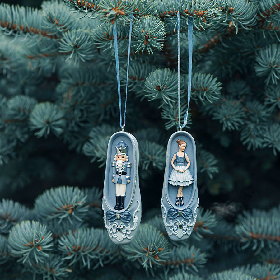 Porsgrunds Porselænsfabrik PP Jul Ballerina Sko Hengepynt 2pk 11cm hengepynt med ballerina og nøtteknekker plassert blant juletrær.