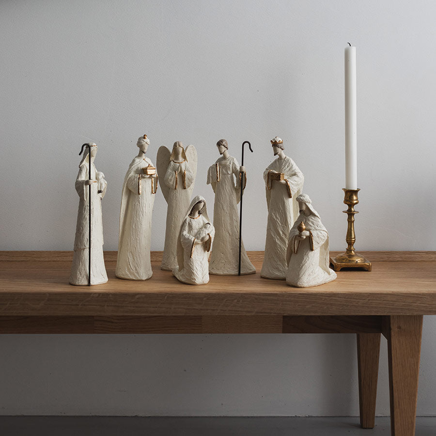 Christiania 1739 Julekolleksjon Julekrybbe Sett 7 Deler Hvit: utvalg av hvite julekrybbefigurer vises i en stilren innredning med lys og blomster.