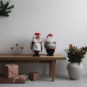 To julefigurer fra Christiania 1739, nissemor og nissefar, dekorativt plassert på et bord med juledekorasjoner, skaper koselig julestemning.