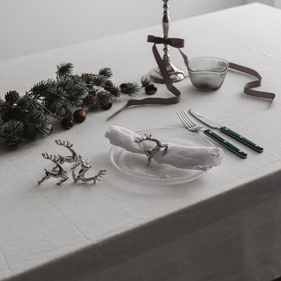 Elegant dekket julebord med serviettringer i reinsdyrdesign fra CHRISTIANIA 1739, komplett med sølvtallerkener og pyntegjenstander.