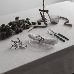 Elegant dekket julebord med serviettringer i reinsdyrdesign fra CHRISTIANIA 1739, komplett med sølvtallerkener og pyntegjenstander.