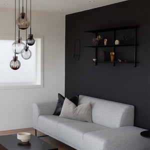 Stueinnredning med Hadeland Glassverk krystallkule taklampe, plassert over en grå sofa for et elegant og moderne uttrykk.