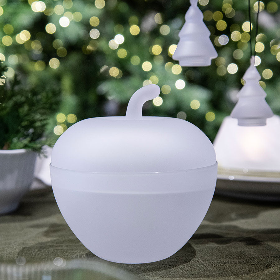 Hadeland Glassverk glasseple plassert på et bord med julepynt i bakgrunnen, viser et tidløst design som skaper hygge og varme i rommet.