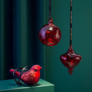 Elegant Hadeland Glassverk Fugleklang julepynt, med en glitrende fugl og to glasskuler i rødt, som skaper en klassisk julestemning.