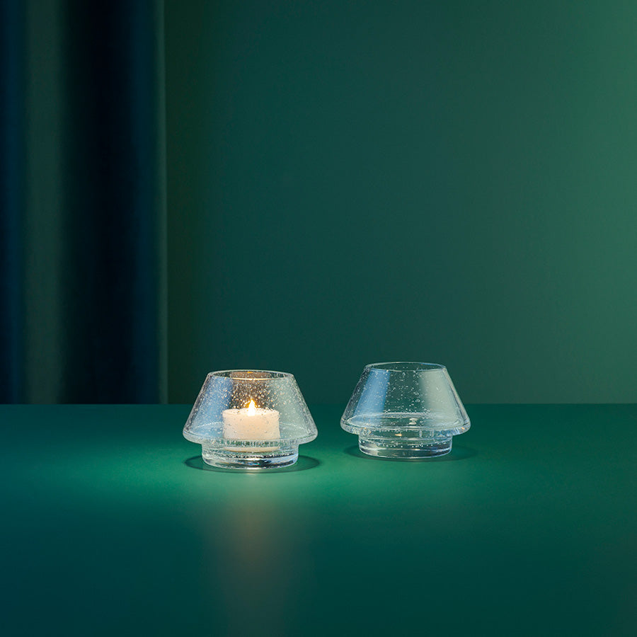 Hadeland Glassverk Gran Lyslykt Klar m/Bobler 2pk, lyslykter på en grønn overflate med lys, skaper en varm og koselig atmosfære.