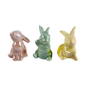 Tre dekorative keramiske harer i pastellfarger - rosa, grønn og gul - med glansfull finish. Hver hare har unike detaljer og står 8 cm høye.