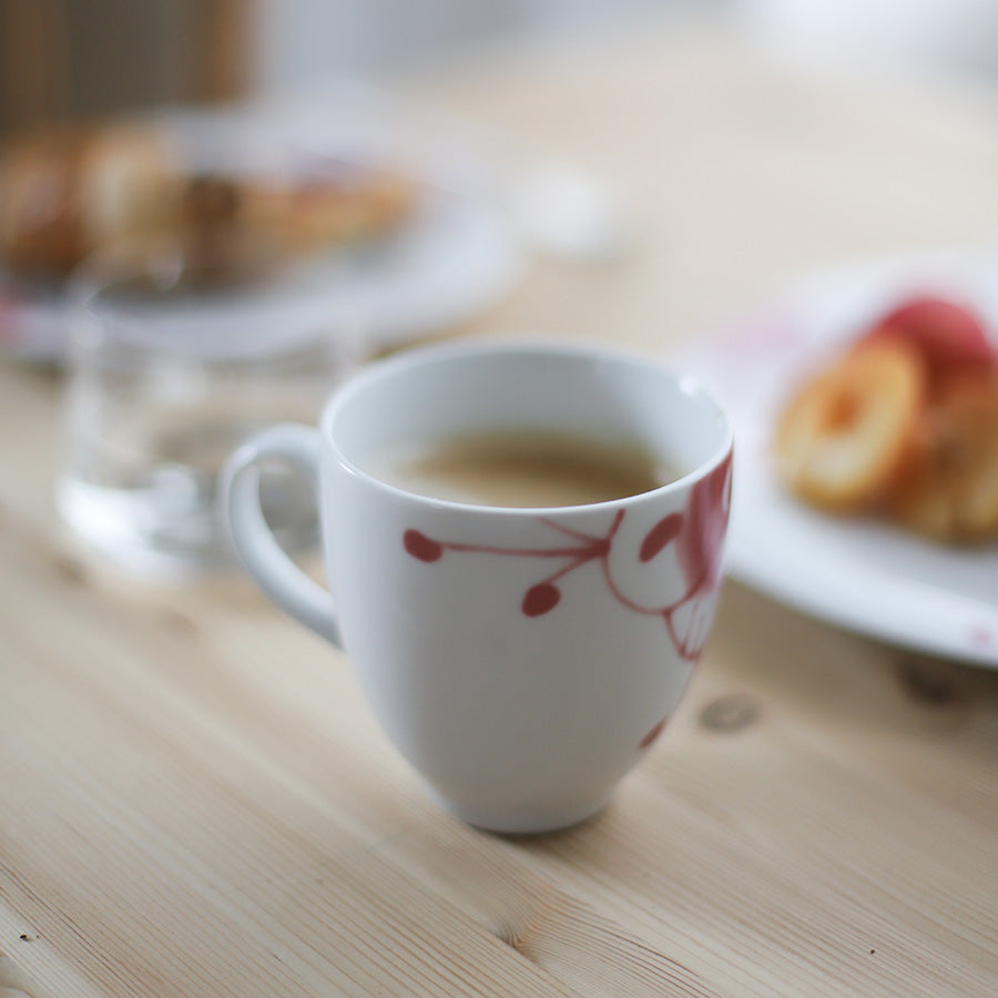 Porsgrund Porselænsfabrik Maxistrå Krus 35cl Nomi Rosa fylt med kaffe, plassert på et bord dekoreret med bakverk.
