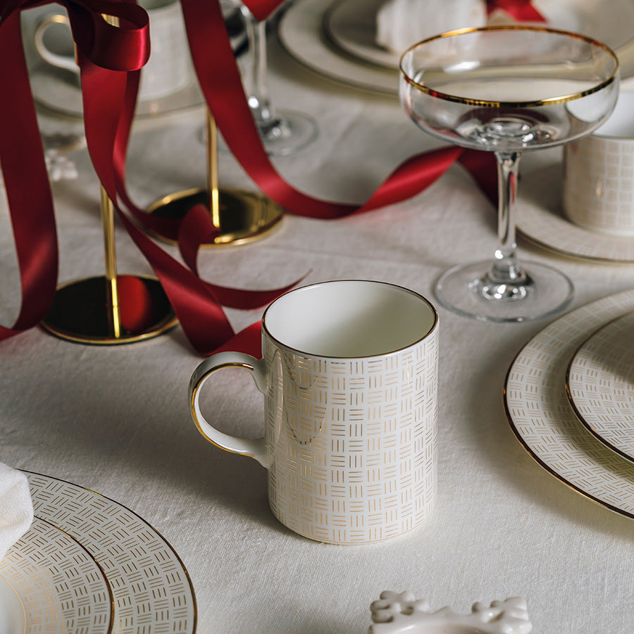 Porsgrunn Porselænsfabrik Vivienne Gull Krus 35cl plassert på et elegant dekket bord med røde bånd, perfekt for spesielle anledninger.