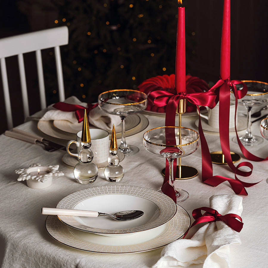 Elegant borddekking med Porsgrund Porselænsfabrik Vivienne Gull Dyp Tallerken 23 cm, som viser en festlig atmosfære med røde lys og dekorasjoner.