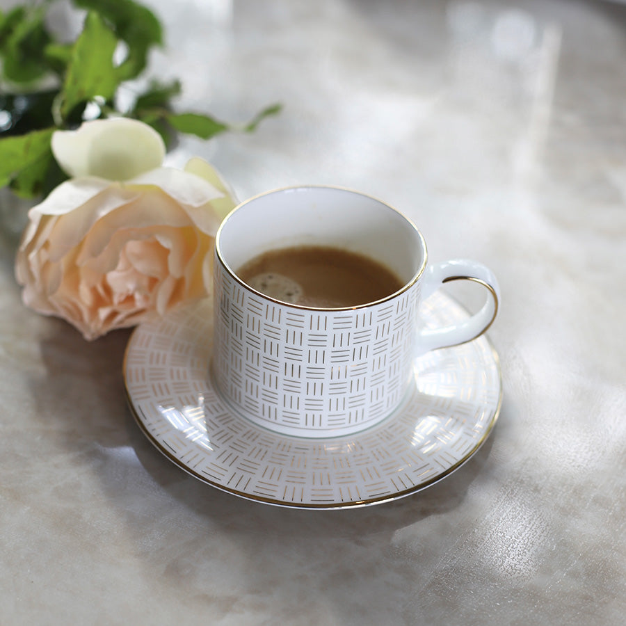 Porsgrund Porselænsfabrik Vivienne Gull Tekopp med skål, servert med kaffe og en rose, elegant bordsetting.
