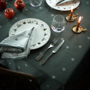 Nærbilde av Wik & Walsøe damaskduk i grønn med klassiske julemotiver, perfekt for julefeiringer.