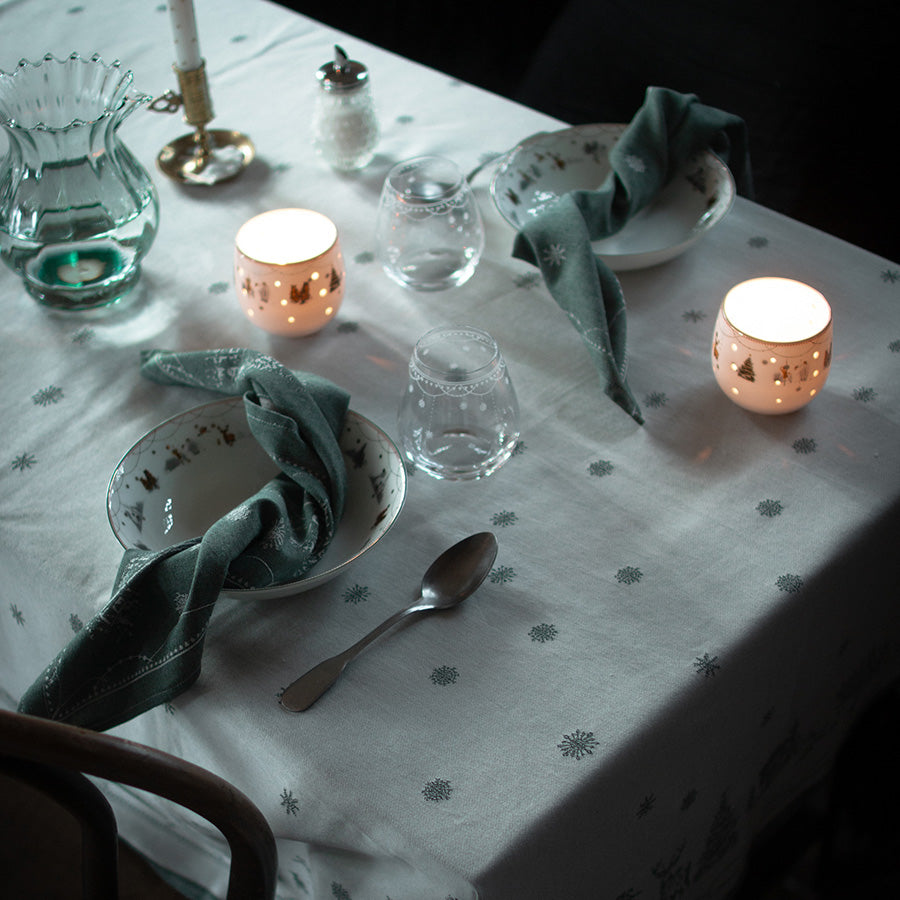 Elegant borddekk med Wik & Walsøe hvit damaskduk, dekorert med stearinlys og serviser, skaper en vakker julehøst.