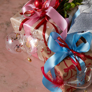 Holmegaard julekule kombinert med gaver, dekorert med bånd i rosa og rødt, fremhever den klassiske julestilen designet av Ann-Sofi Romme.