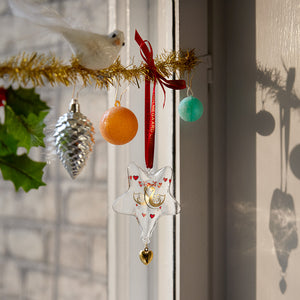 Holmegaard julestjerne hengende i en festlig dekorasjon, med fargerike ornamenter og en kunstnerisk utsmykking av glass, perfekt for julepynt.
