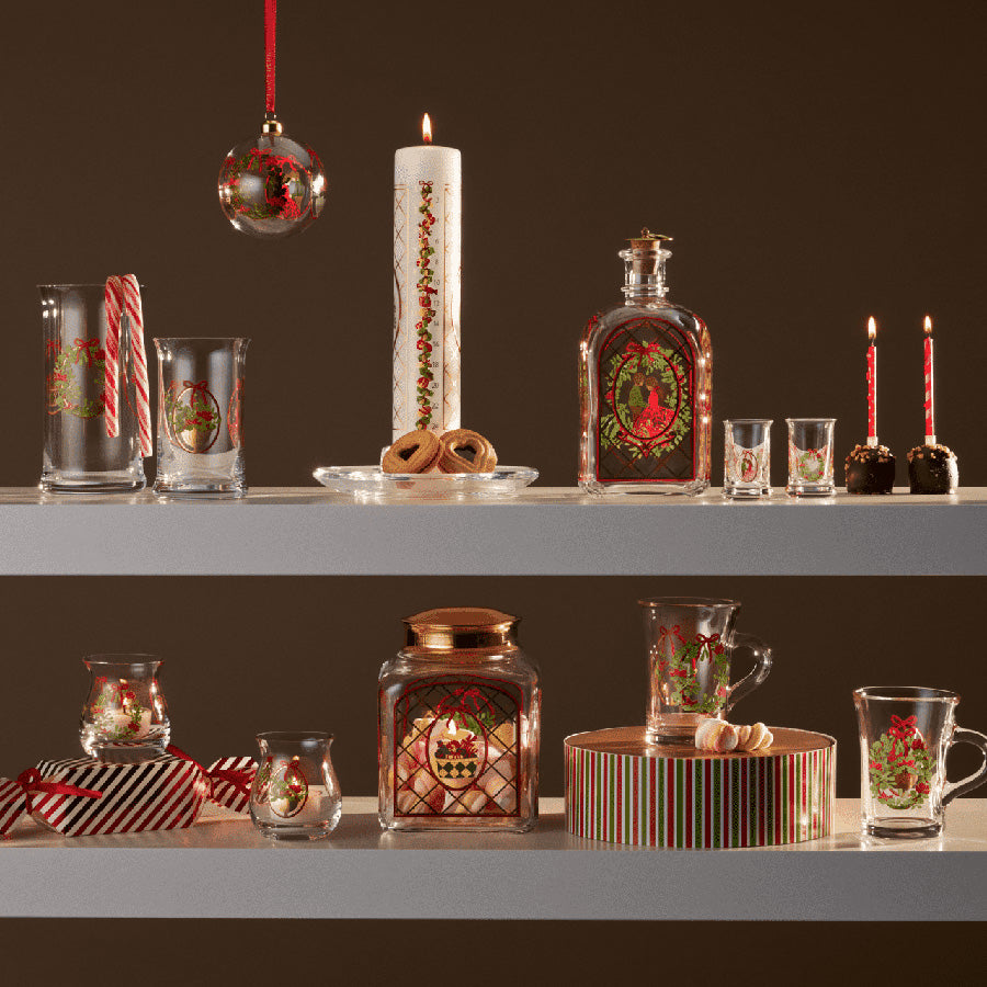 Holmegaard kalenderlys 2025 plassert mellom ulike juledekorer, inkludert glassvarer og julevarer, som gir et nostalgisk juleuttrykk.