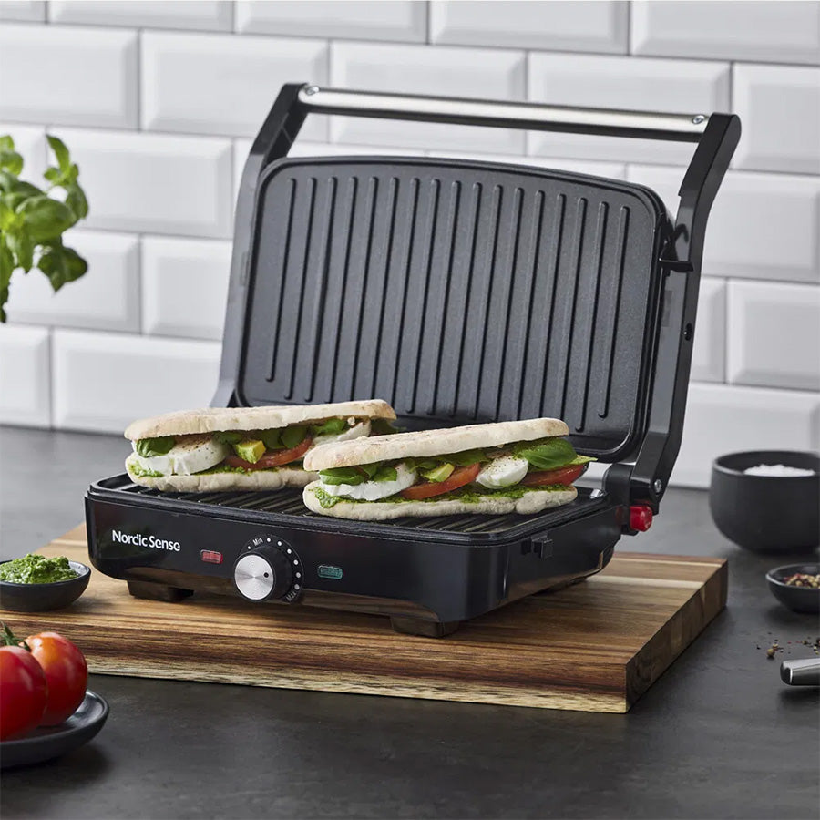 Nordic Sense Paninigrill i bruk med to fyllte paninier, presentert på et skjærebrett, inspirerende muligheter for middag og frokost.