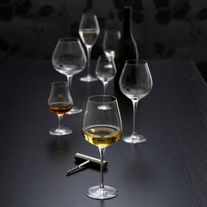 Hadeland Glassverk Odyssé Cognacglass 24cl sammen med flere typer glass som pryder et mørkt bord, i en elegant setting.
