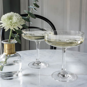 Hadeland Glassverk Odyssé Cavaskål 25cl 6pk - To glass fylt med sprudlende drinker, plassert på marmoroverflate med blomsterdekor.