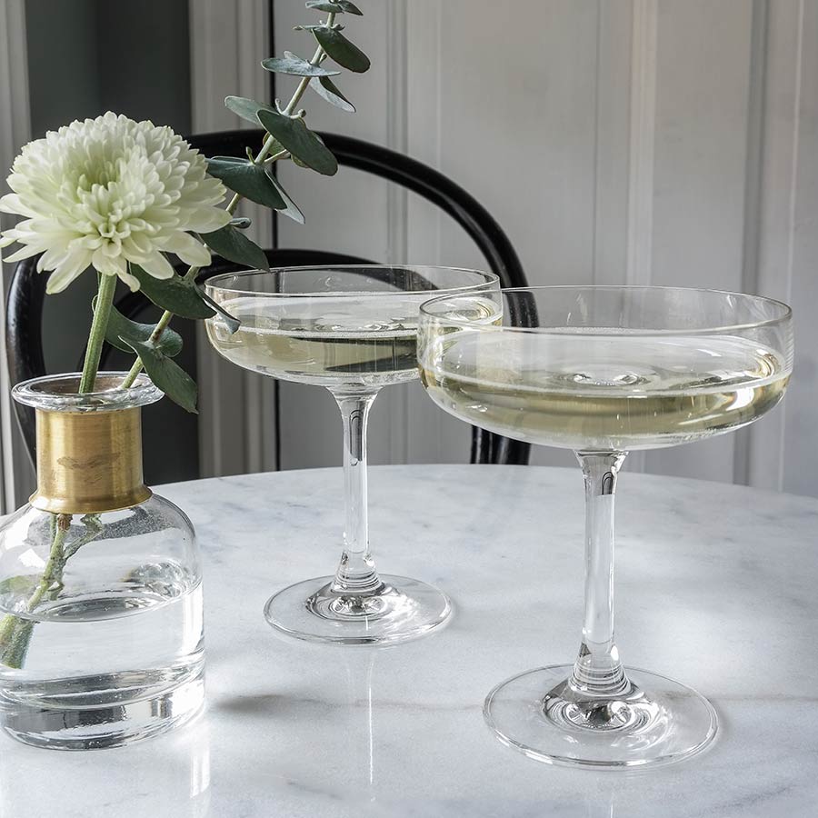 Hadeland Glassverk Odyssé Cavaskål 25cl 6pk - To glass fylt med sprudlende drinker, plassert på marmoroverflate med blomsterdekor.