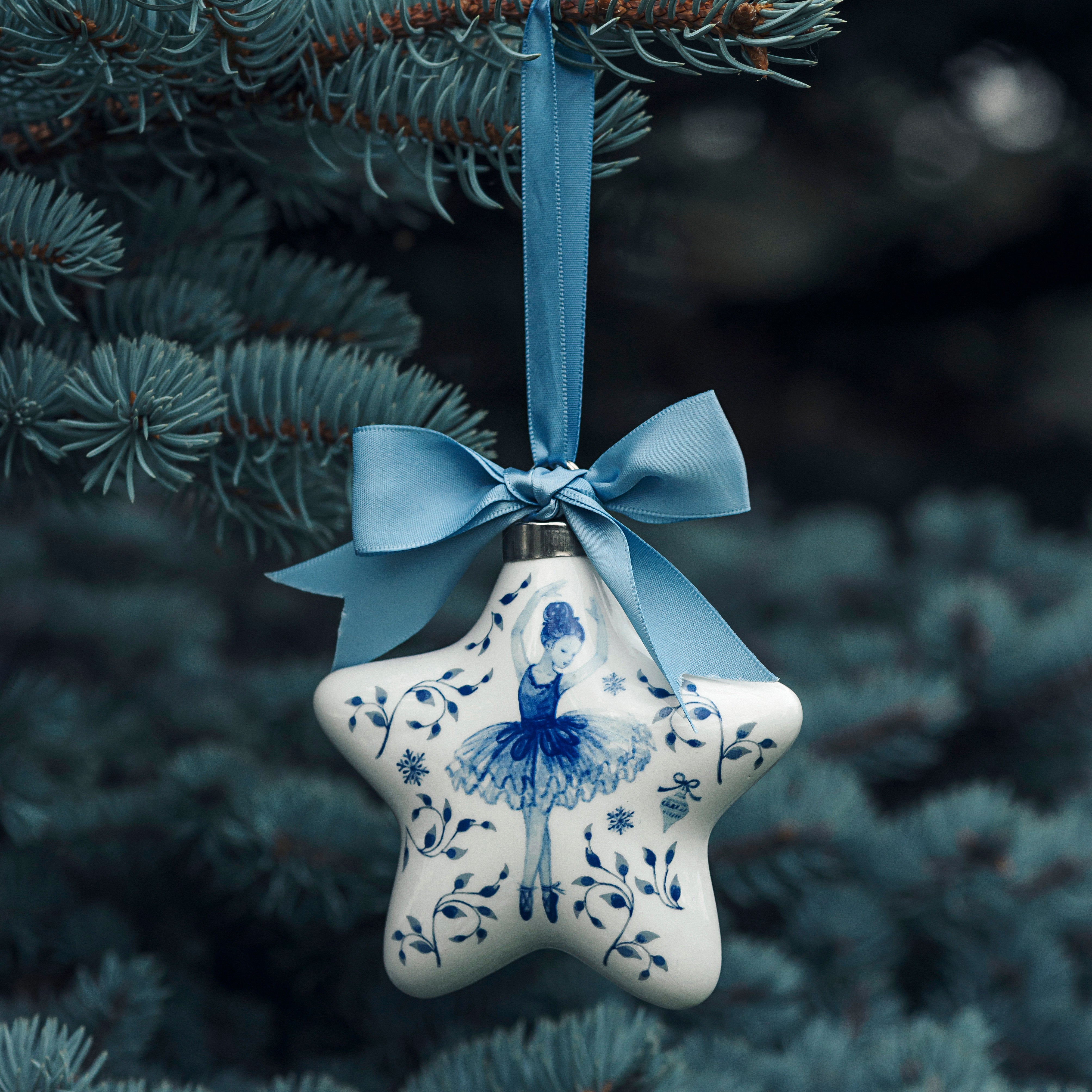 Porsgrunds Porselænsfabrik PP Jul Ballerina Stjerne Hengepynt 9cm Blå hengende i en grønn gran med dekorativt blått sløyfebånd, ideell julepynt.