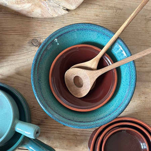 Porsgrunds Porselænsfabrik Terra serveringsbolle 38cm Verde med to tre skjeer, plassert sammen med mindre boller i terrakotta.