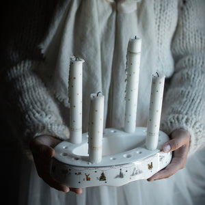 Person som holder Wik & Walsøe Julemorgen Story adventsstake med lys, utstrålende en nostalgisk julefølelse.