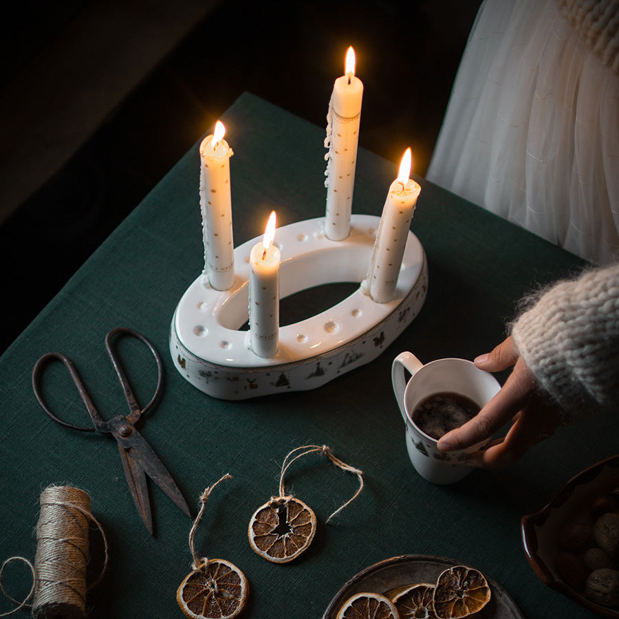 Wik & Walsøe Julemorgen Story adventsstake med tente lys, sammen med juledekorasjoner som tørkede skiver av frukt.