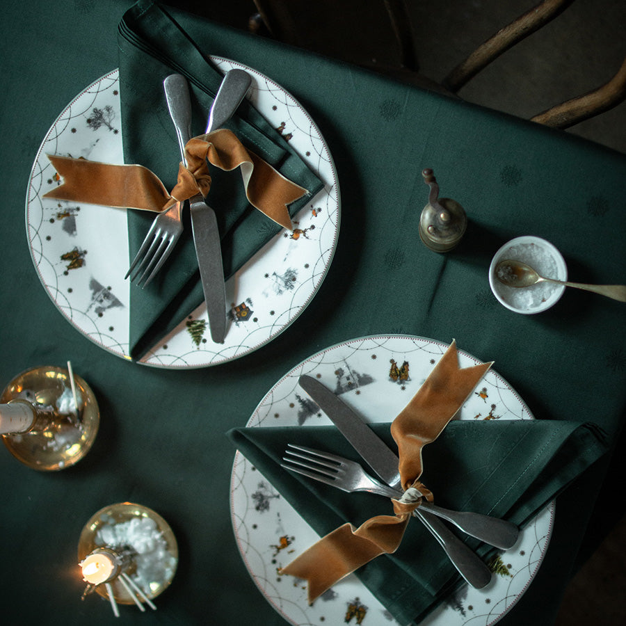 Nærbilde av borddekkingen med Wik & Walsøe Julemorgen servietter i grønn, elegant viklet inn med en satinbånd, perfekt for festlige anledninger.