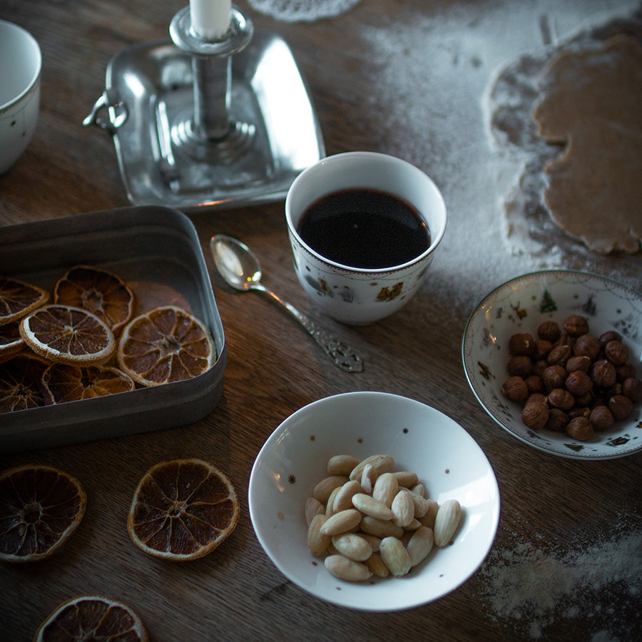 Julekopp fra Wik & Walsøe på et rustikt trebord, omgitt av tørkede frukter og flere snacks, en festlig setting for julefeiring.