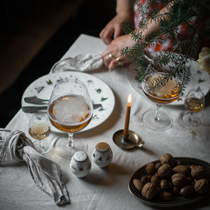 Koselig middagsscene med Wik & Walsøe Julemorgen salt- og pepperbøsse, servering av drink og nøtter, pyntet med en gran.