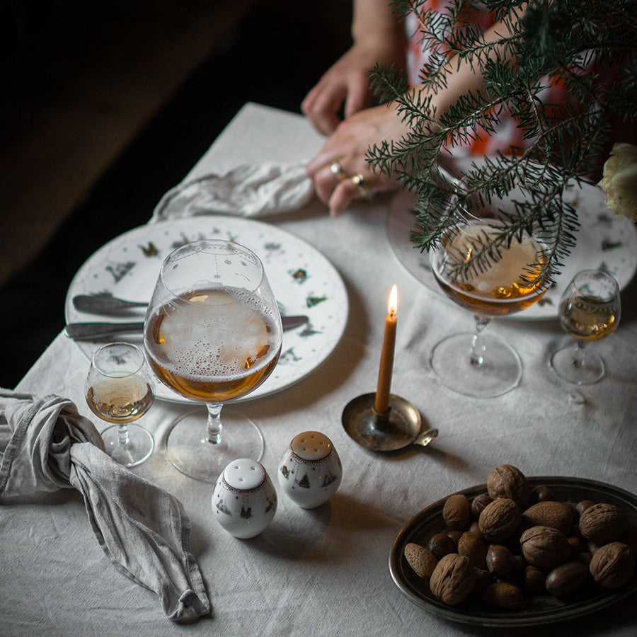 Koselig middagsscene med Wik & Walsøe Julemorgen salt- og pepperbøsse, servering av drink og nøtter, pyntet med en gran.
