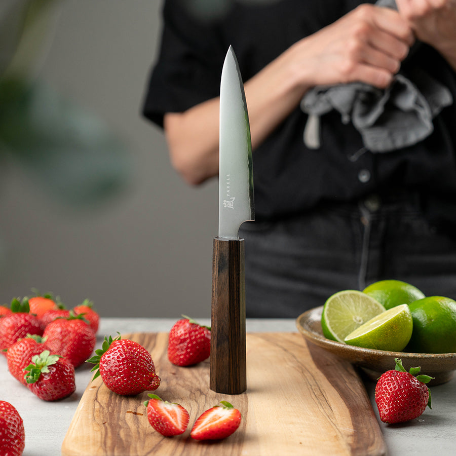 Yaxell Hana Universalkniv 12cm i bruk, ideell for hakking av urter og skjæring av grønnsaker.