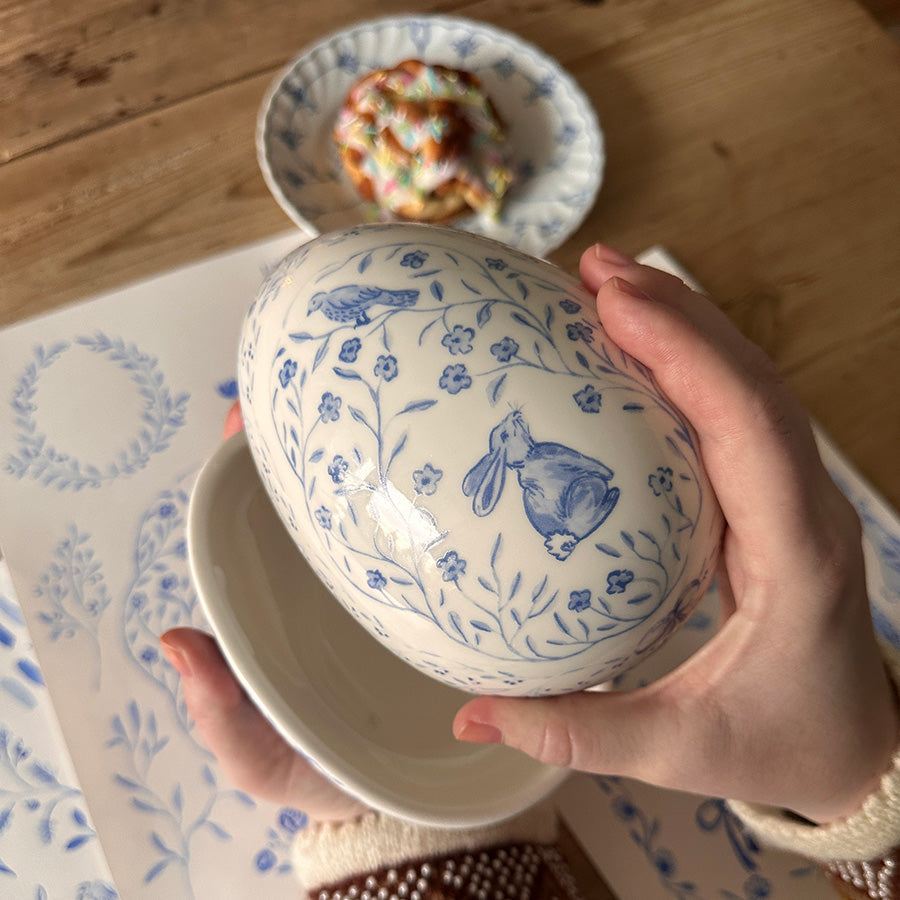 Dekorative påskeegg i pastellfarger henger fra grener i en vase, og gir en vakker påskedekorasjon i moderne stil.