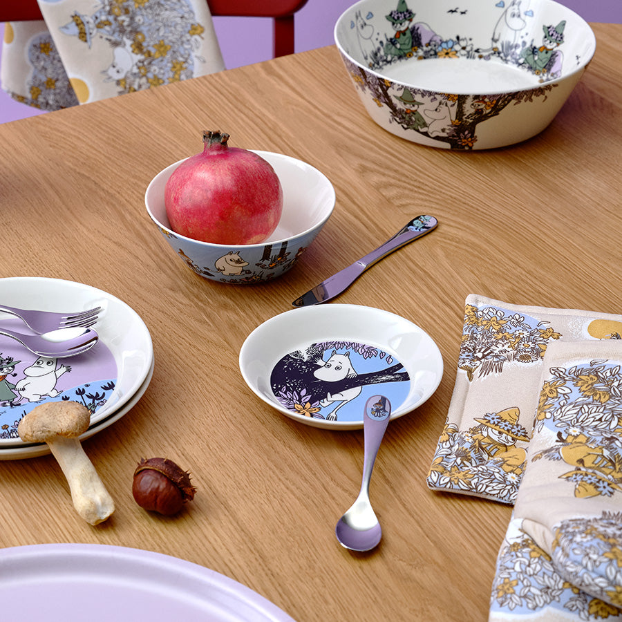 Kreativ borddekorasjon med Moomin asjetter og skåler, inkludert flere motiver av Mummitrollet, ideelt for hyggelige måltider.