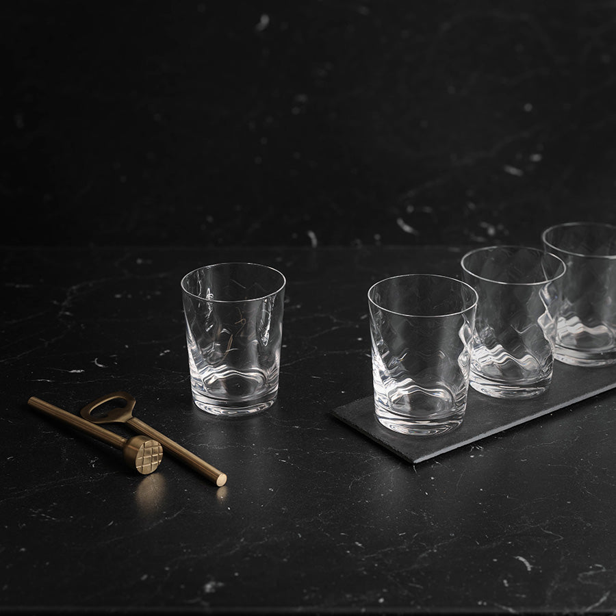 Vannglass med elegant design plassert på en mørk overflate, ideelt for servering av drikke.
