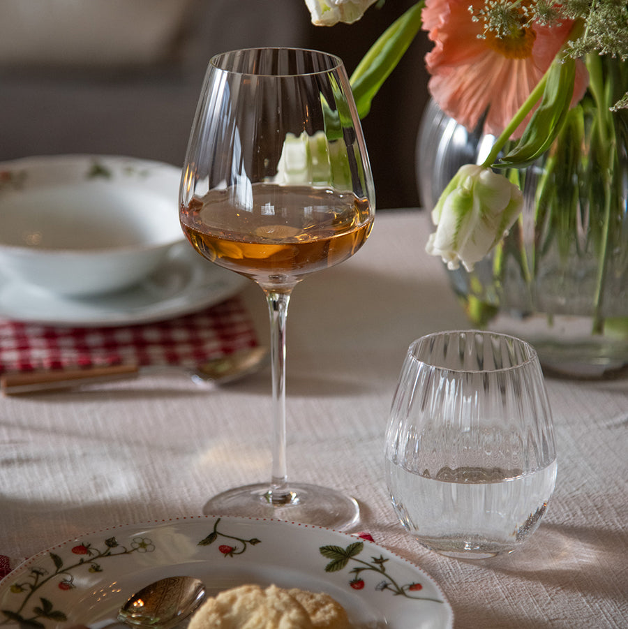 Hadeland Glassverk Prestige vannglass på dekket bord, kombinert med vinglass, blomster og mat, ideelt for middagsselskap.