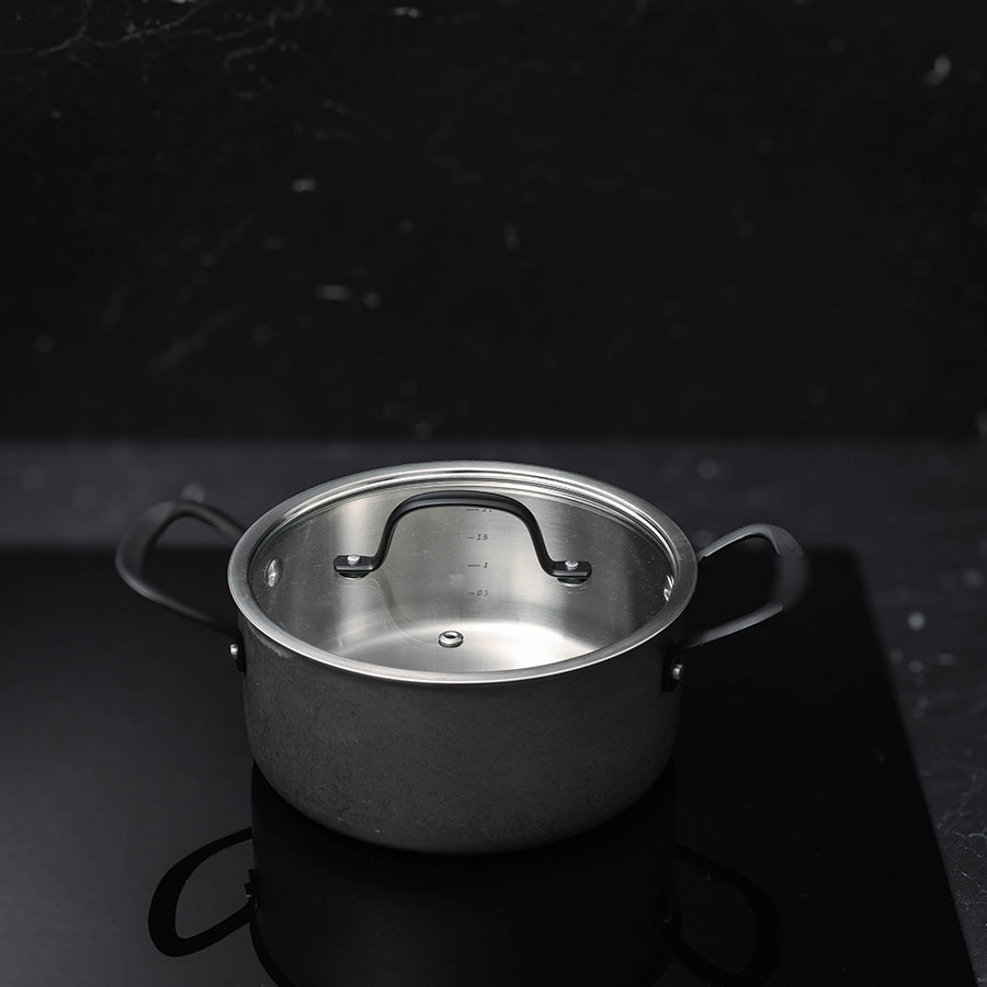 Detaljbilde av en liten kasserolle i grytesettet, laget av rustfritt stål med et stilrent design. Passer perfekt til presise matlagingsoppgaver.