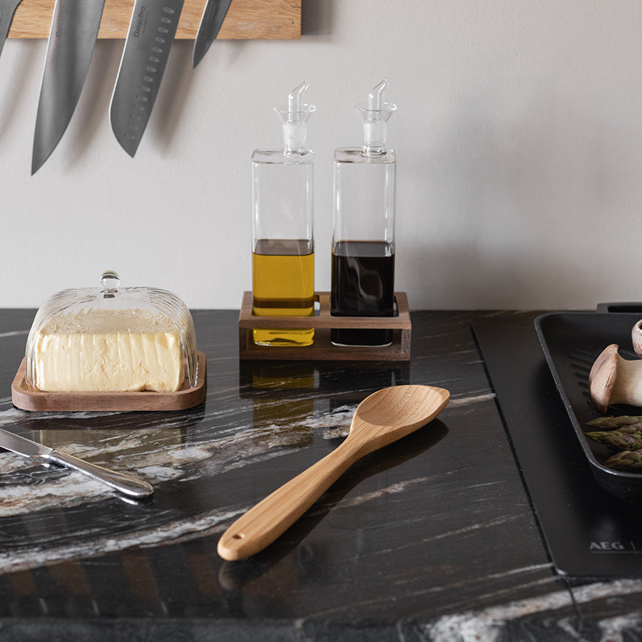 Bambus serveringsskje plassert på en elegant kjøkkenbenk med olivenolje og balsamico, perfekt for både matlaging og servering.