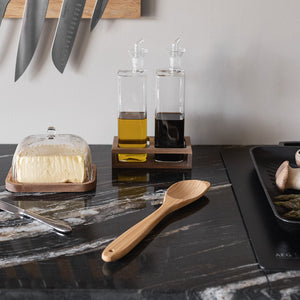 Bambus serveringsskje plassert på en elegant kjøkkenbenk med olivenolje og balsamico, perfekt for både matlaging og servering.