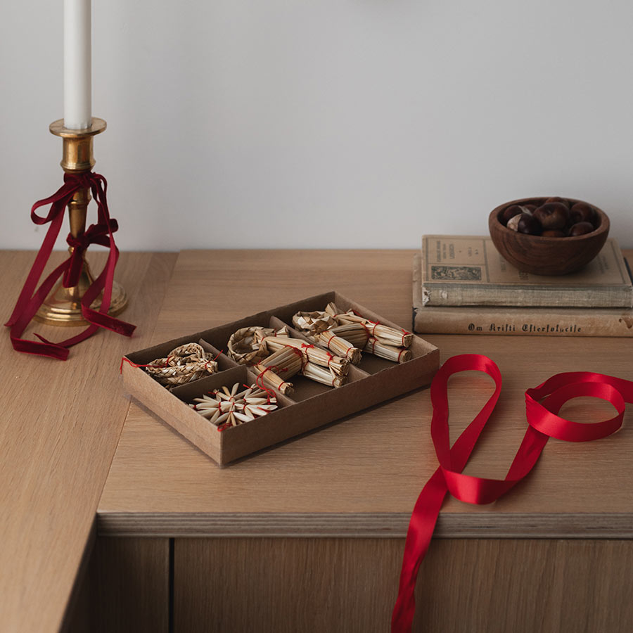 Christiania 1739 Julekolleksjon Hengepynt Julebukk, Hjerte & Stjerne 10pk, dekorativt arrangert på et trebord med røde bånd.