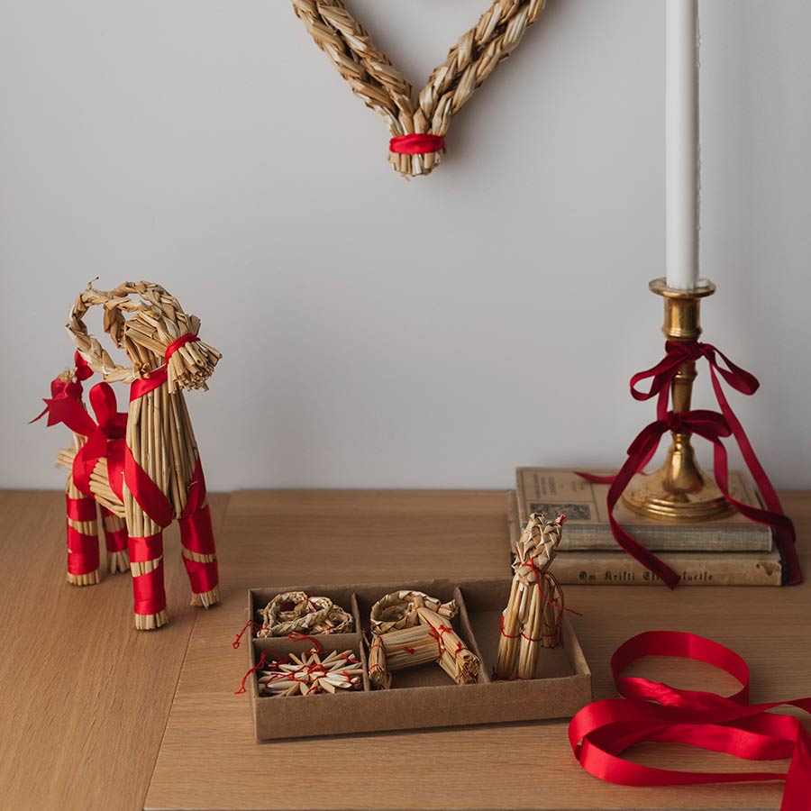 Christiania 1739 Julekolleksjon Hengepynt Julebukk, Hjerte & Stjerne 10pk, presentert sammen med en dekorativ halmfigur og røde elementer.