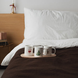 Christiania 1739 Julekolleksjon Kurs M/Juletremotiv 30cl, tre julekopper med ulike motiv plassert på et brett i en koselig sengemiljø.