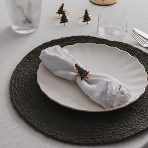 Christiania 1739 Julekolleksjon serviettringer med juletremotiv stilt opp på et dekket bord med servietter og tallerken, perfekt for julefeiring.