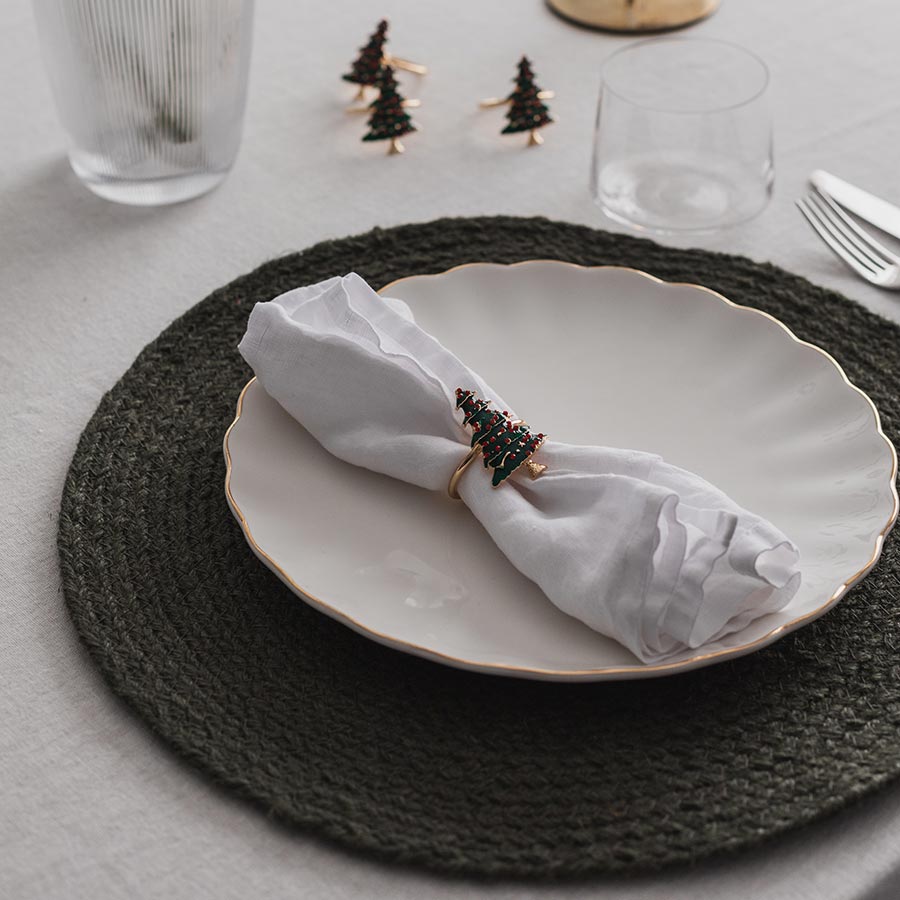 Christiania 1739 Julekolleksjon serviettringer med juletremotiv stilt opp på et dekket bord med servietter og tallerken, perfekt for julefeiring.