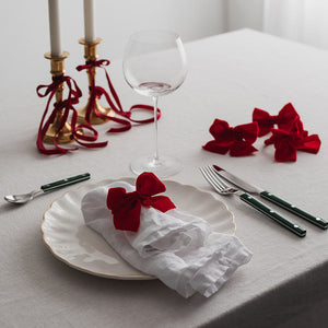 Juledekket bord med Christiania 1739 serviettringer in rød sløyfe, hvor servietter og glass skaper en festlig atmosfære.