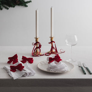 Stilfullt bord dekket med Christiania 1739 serviettringer i rød sløyfe, lysestaker og glass som skaper et koselig julemiljø.