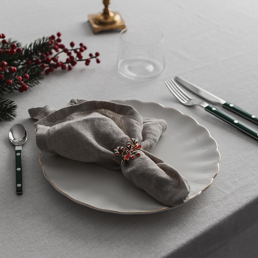 Borddekk med Christiania 1739 Julekolleksjon Serviettring Sukkertøy, som holder en grå serviett, omringet av juledekorasjoner. Ideelt for en leken og festlig julemiddag.