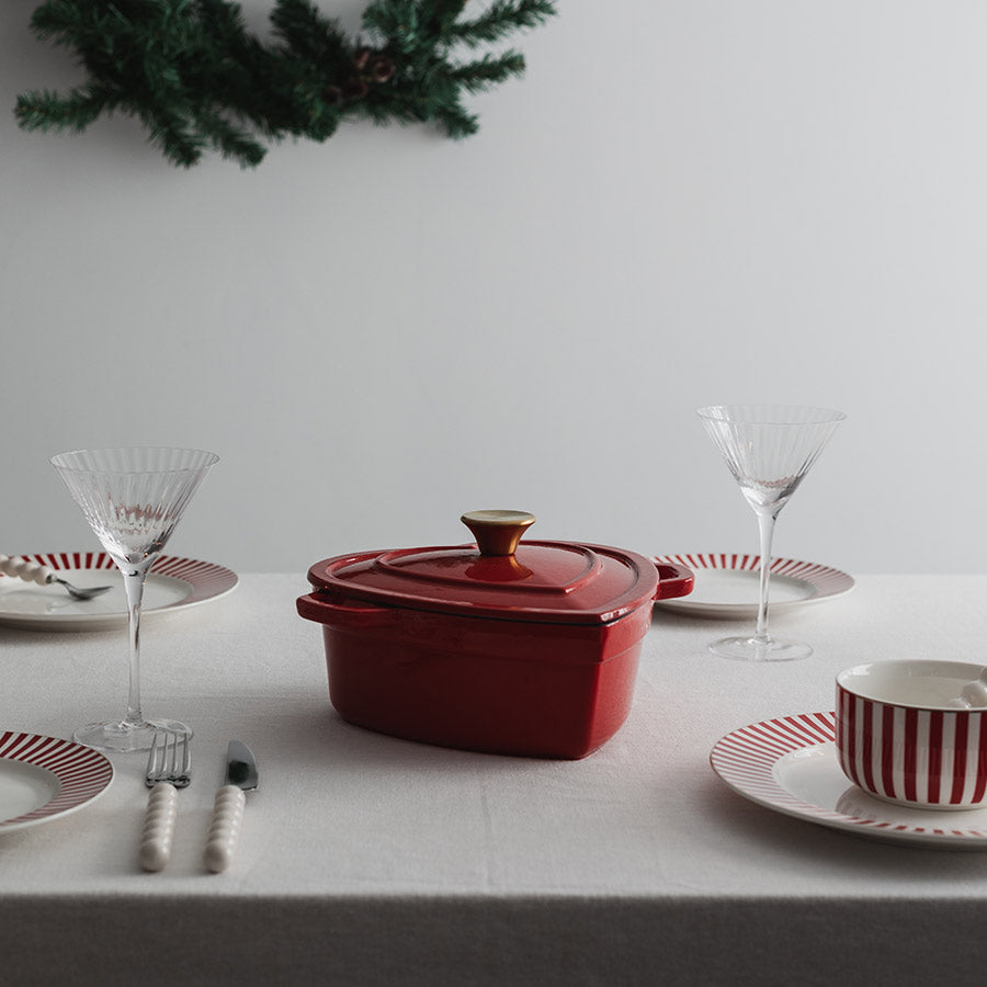 Christiania 1739 Julekolleksjon Støpejerngryte Hjerte 2.8l Rød, elegant plassert på et dekket festbord med glass.