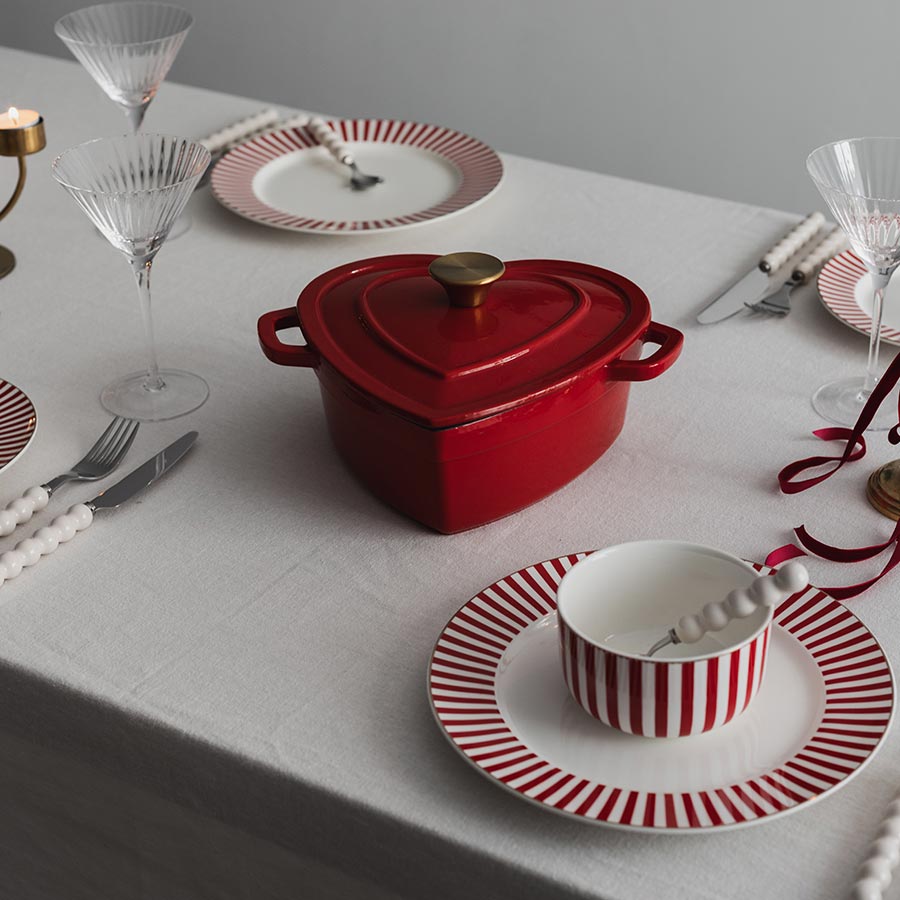 Christiania 1739 Julekolleksjon Støpejerngryte Hjerte 2.8l Rød midt på bordet, omringet av festlige tallerkener.